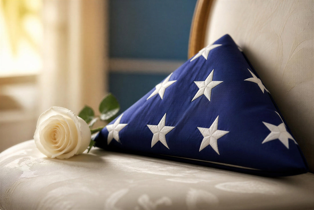 Folded American flag resting against a cream chair with a single white rose beside it, soft warm light — memorial image for a female veteran's funeral program