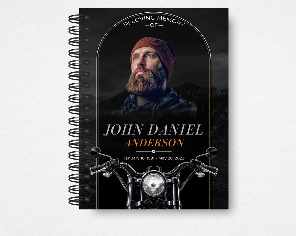 Beyond the Open Road memorial guest book front cover, black spiral-bound design with a bearded man in a rust-colored beanie, copper arch, white and copper lettering, motorcycle handlebars and headlight, Standard size.