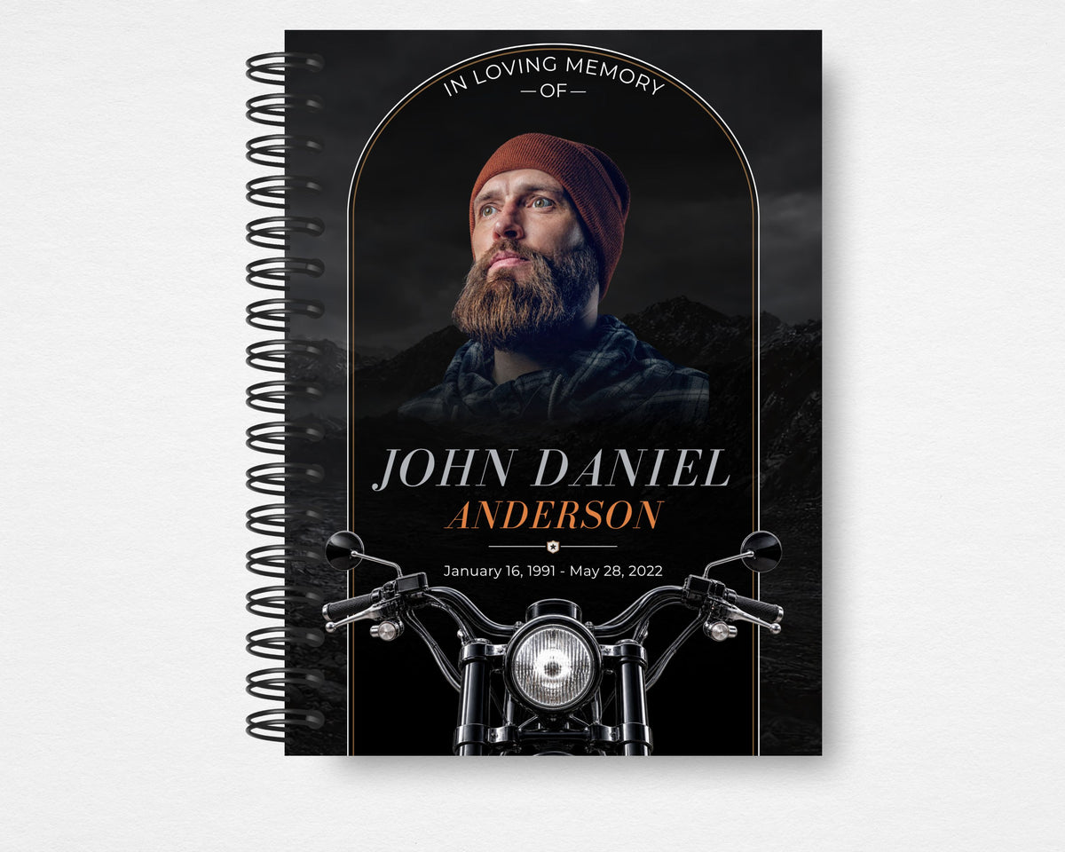 Beyond the Open Road memorial guest book front cover, black spiral-bound design with a bearded man in a rust-colored beanie, copper arch, white and copper lettering, motorcycle handlebars and headlight, Standard size.